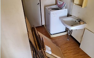 洗濯機や家具が残った洗面所を即日で片付けた事例（作業前）